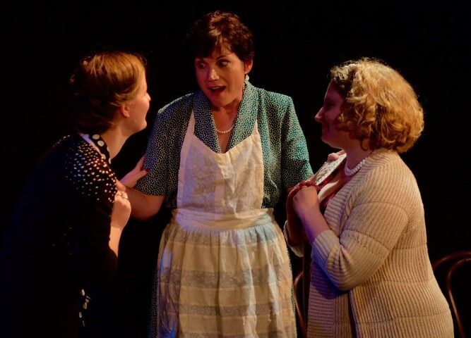 Photo of three women dressed in 1940s costumes, gossiping.