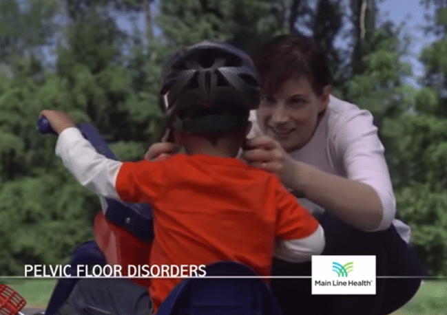 Still from a Main Line Health commercial featuring a woman tightening a little boy's bike helmet.